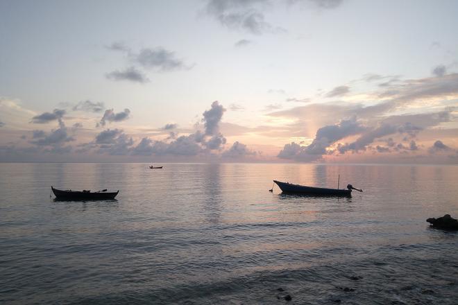 Boats at sea at sunset in the Maldives.