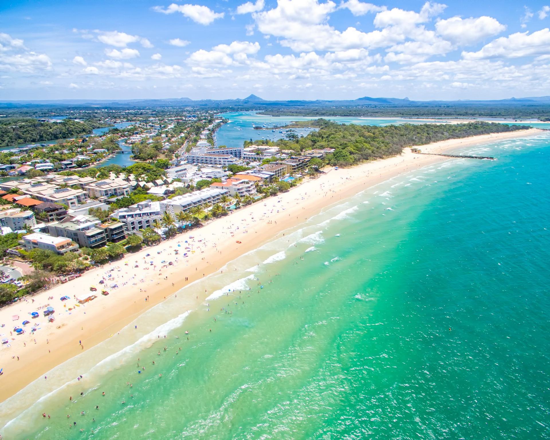 Aerial view of beach with a lot of people in Noosa Heads in sunny weather with few clouds